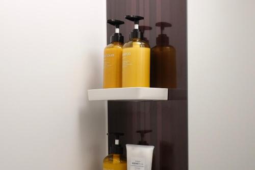 a shelf with four bottles of hair products on it at ROOMs 001 カフェ併設 綺麗なワンルーム 分倍河原駅から徒歩3分 in Fuchu