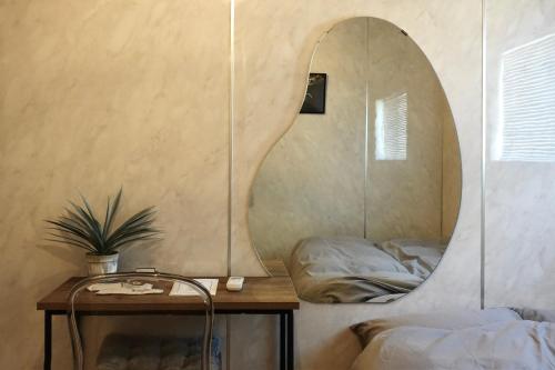 a mirror on a wall in a bedroom with a table at ROOMs 001 カフェ併設 綺麗なワンルーム 分倍河原駅から徒歩3分 in Fuchu