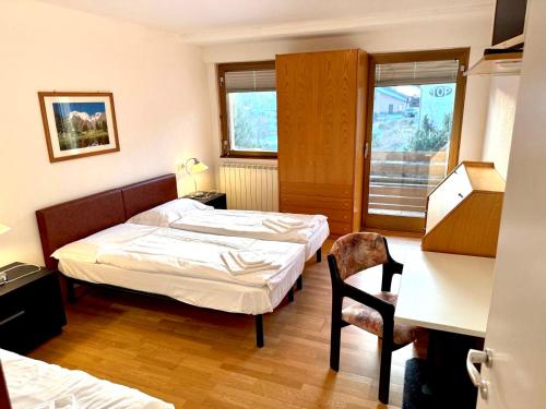 a hotel room with two beds and a chair at Top Residence Trilocale Larice in Passo del Tonale