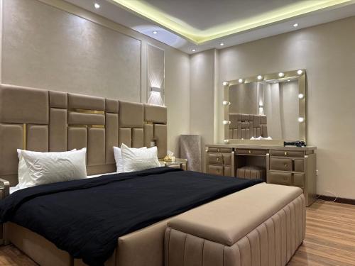 Un dormitorio con una cama grande y un espejo. en New Cairo Hotel Apartment, en Madīnat ash Shurūq