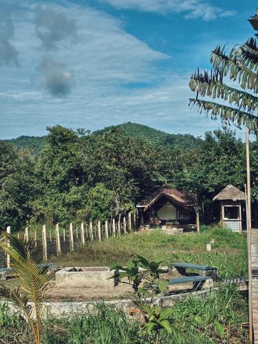 a house in a field with a fence and trees at Cabanas de Nacpan Camping Resort in El Nido