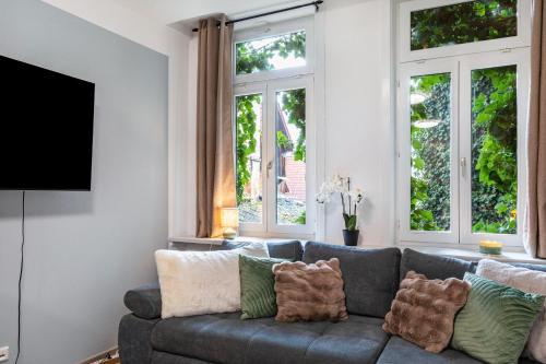 a living room with a gray couch and windows at Marktplatz Ferienwohnung in Alsfeld