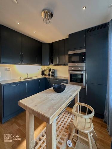 a kitchen with blue cabinets and a wooden table at Modern apartment Hovden ski in-out x-skiing, 2 bathrooms and balcony in Hovden