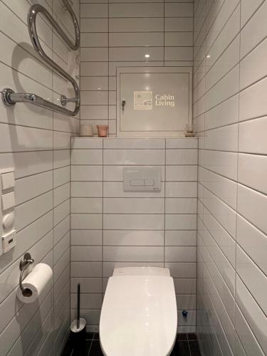 a white bathroom with a toilet and a sign on the wall at Modern apartment Hovden ski in-out x-skiing, 2 bathrooms and balcony in Hovden