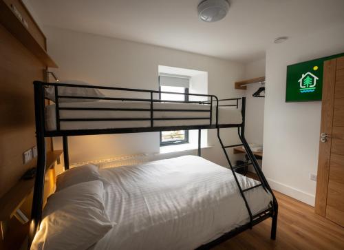 a bedroom with a bunk bed with white sheets at Éalú Lodge in Sligo