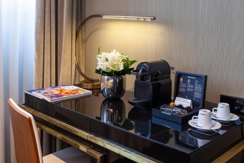 a desk in a hotel room with a coffee maker and flowers at Altis Avenida Hotel in Lisbon