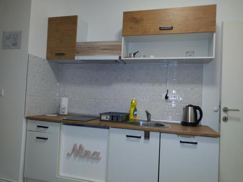 eine Küche mit weißen Schränken und einer Spüle in der Unterkunft Nina centar in Sombor