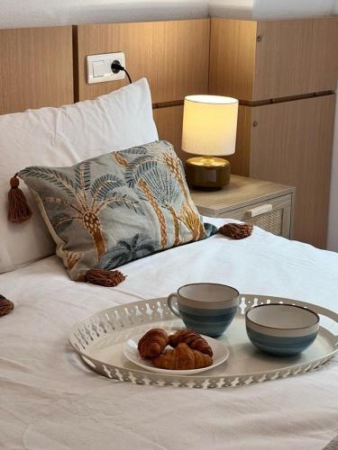 a tray with two bowls and a plate with donuts on a bed at Paraiso en la playa con terraza in El Borseral