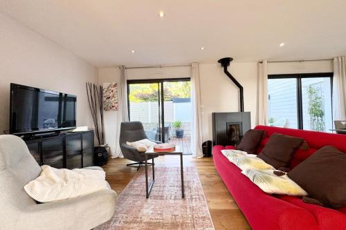 un salon avec un canapé rouge et une télévision dans l'établissement Maison contemporaine de standing - 100m des plages, à Ploemeur