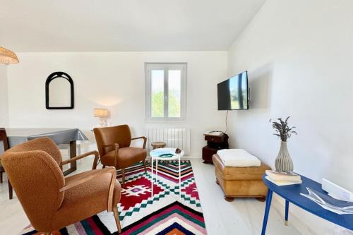 - un salon avec des chaises, une télévision et un tapis dans l'établissement Charmante maison de plain pied - 700m des plages, à Ploemeur