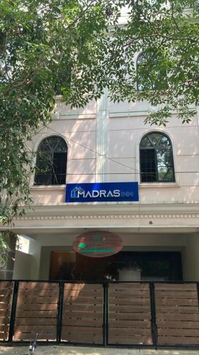 a white building with a blue sign on it at Madras Inn - Alwarpet in Chennai
