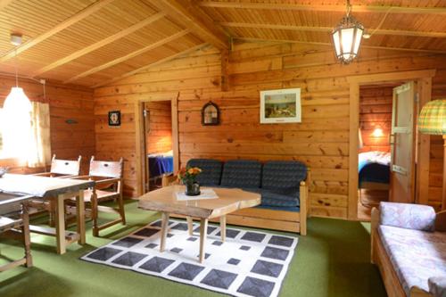 a wooden cabin with a couch and tables in it at Tallhöjden Hotel & Cottage Lodge in Simlångsdalen