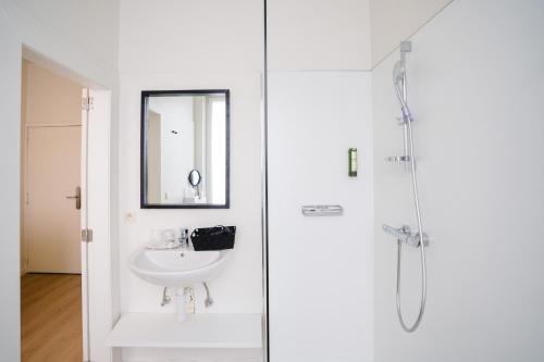 a white bathroom with a sink and a shower at Hotel du Bassin in Ostend