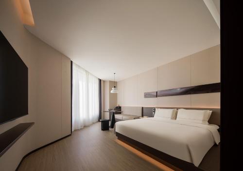 a hotel room with a bed and a television at Atour Hotel Haikou Longhua Jinniuling Park in Haikou