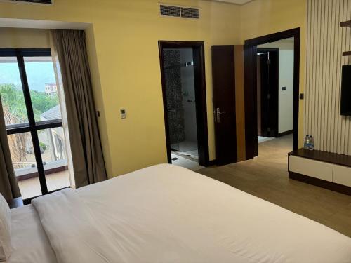 a bedroom with a white bed and a large window at Imperial Plaza Hotel, Juba in Juba