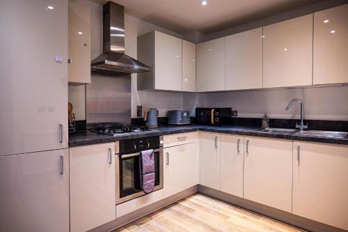 a kitchen with white cabinets and a stove top oven at Spacious 2 Bedroom Apartment in Crawley in Crawley