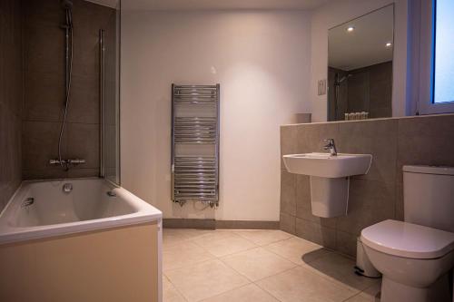 a bathroom with a tub and a toilet and a sink at Spacious 2 Bedroom Apartment in Crawley in Crawley