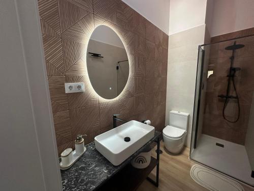 a bathroom with a sink and a mirror and a toilet at Casas Rurales LA HUERTA DEL CURATO I in Tolbaños