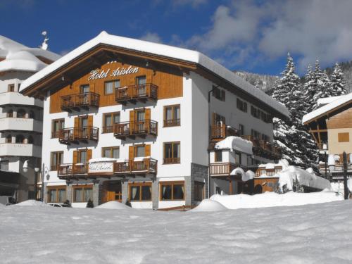 ein großes Gebäude im Schnee mit Schnee in der Unterkunft Hotel Ariston ***S in Madonna di Campiglio