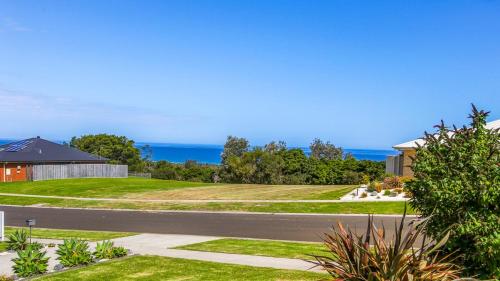 an empty road next to a house and the ocean at Waves and Blossoms in Cunninghame