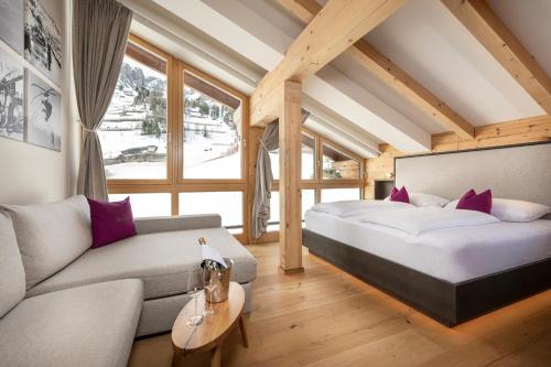 sypialnia z dużym łóżkiem i kanapą w obiekcie Austria Alpinhotel Ski IN Ski OUT an der Edelweissbahn w mieście Obertauern