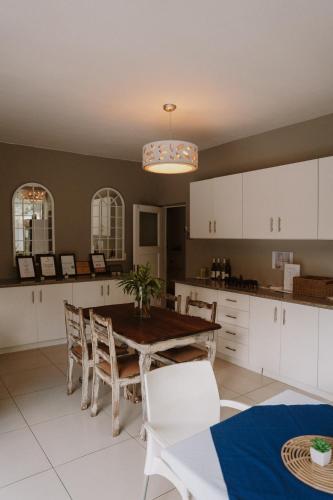 a kitchen with a wooden table and white cabinets at Caza Beach Guesthouse in Durban
