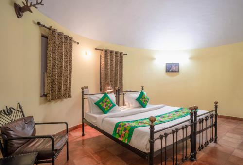 a bedroom with a bed and a chair at Treebo Premium Mowgli's Den, Pench in Khawāsa