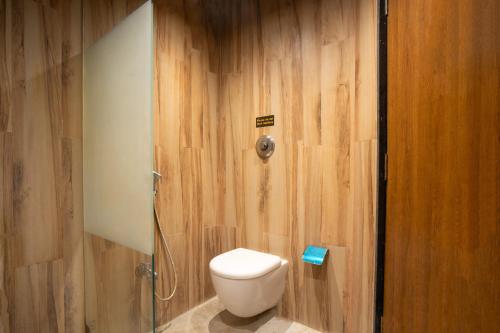 a bathroom with a toilet and a wooden wall at Treebo Premium Mowgli's Den, Pench in Khawāsa