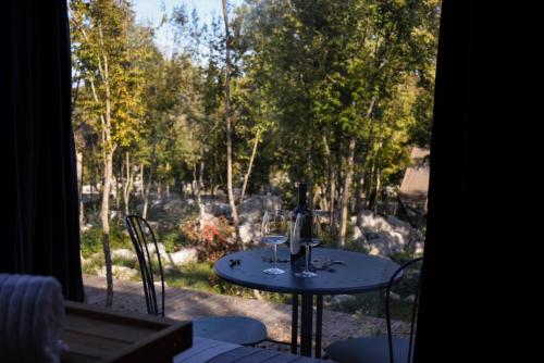 a table with two wine glasses on it on a patio at Oblun Eco Resort - Mirror Cabin in Podgorica