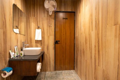 a bathroom with a sink and a wooden wall at Treebo Premium Mowgli's Den, Pench in Khawāsa