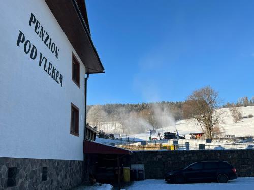 a car parked in front of a snow covered building at Penzion pod Vlekem Dolní Morava in Dolní Morava