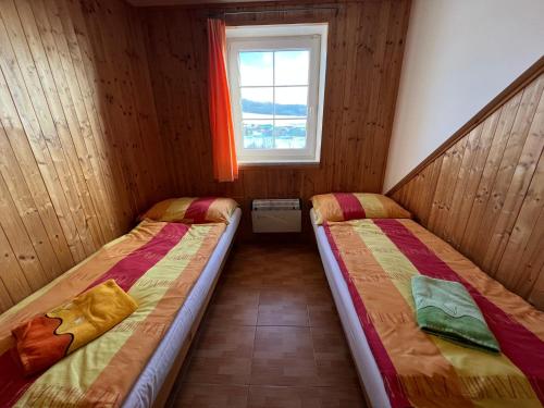 two beds in a small room with a window at Penzion pod Vlekem Dolní Morava in Dolní Morava