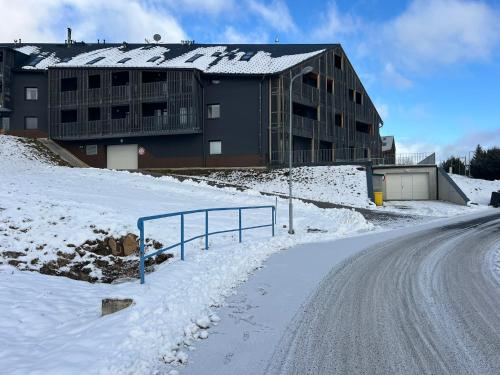 a building on a snow covered hill with a road at Penzion pod Vlekem Dolní Morava in Dolní Morava