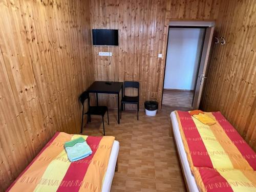 a room with two beds and a table and a door at Penzion pod Vlekem Dolní Morava in Dolní Morava