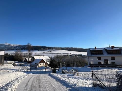 a snow covered road with a house in the distance at Penzion pod Vlekem Dolní Morava in Dolní Morava