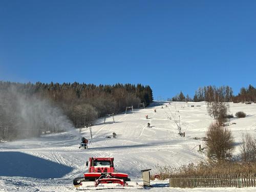 a red truck driving down a snow covered ski slope at Penzion pod Vlekem Dolní Morava in Dolní Morava