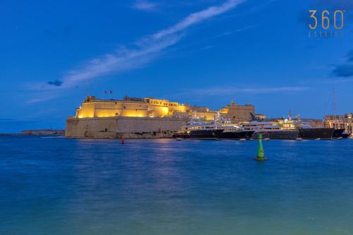 a building in the water in front of a harbor at Maltese Maisonette in Historic Isla with Sea Views by 360 Estates in Senglea