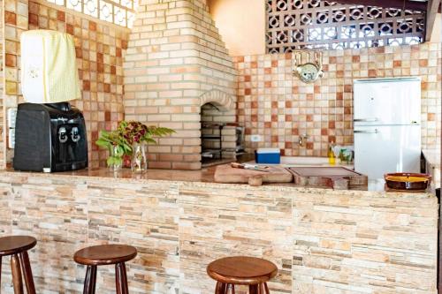 a kitchen with wooden stools and a brick wall at Praia de Juquehy a 5 minutos | Charme Rústico in São Sebastião