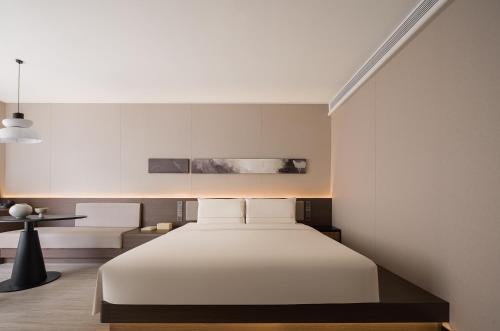a bedroom with a white bed and a table at Atour Hotel Haikou Longhua Jinniuling Park in Haikou