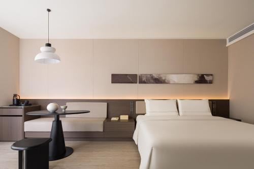 a bedroom with a white bed and a table at Atour Hotel Haikou Longhua Jinniuling Park in Haikou