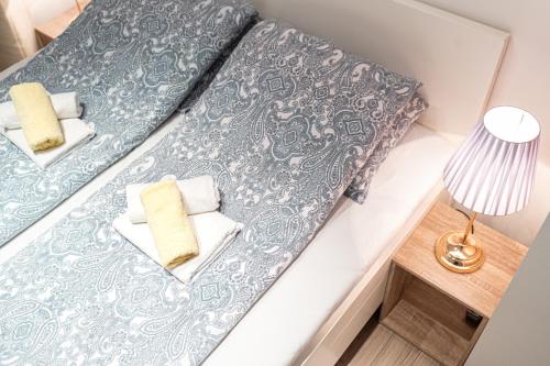 two beds with blue and white pillows and a lamp at Address Apartment Sarajevo in Sarajevo