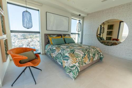 a bedroom with a bed and a mirror and a chair at Oasis on the 27th, Mercury Tower in St Julian's