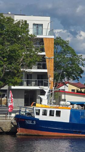 a boat sitting in the water in front of a building at Art Boulevard in Mrzeżyno