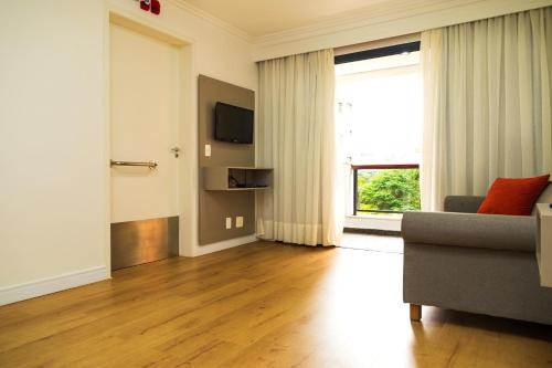 a living room with a couch and a large window at Transamerica Executive Higienópolis in Sao Paulo