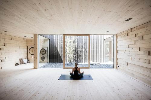 a woman sitting on a yoga mat in a room at Adler Spa Resort Balance in Ortisei