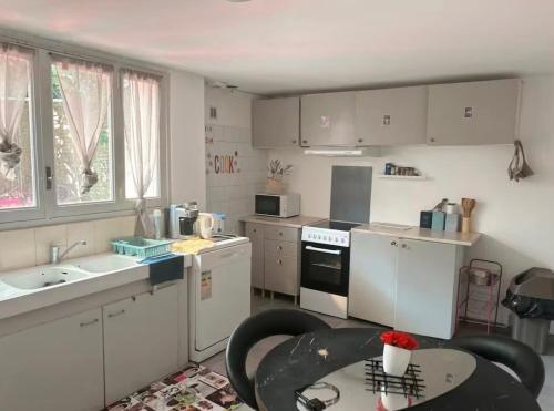 une cuisine avec des armoires blanches, une table et un évier dans l'établissement Iris, à Graulhet