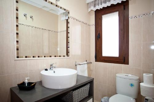 a bathroom with a sink and a toilet and a mirror at A 15 minutos Granada, piscina, jacuzzi, barbacoa in Güevéjar