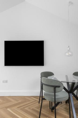 a dining room with two chairs and a table and a tv at Navigation Yard in Chelmsford