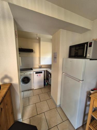Il comprend une cuisine équipée d'un réfrigérateur blanc et d'un lave-linge. dans l'établissement Appartement Saint Lary Soulan centre-ville, à Saint-Lary-Soulan