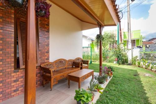 a patio with two benches and a table at Belgareti Modern Ethnic House Cipanas Puncak in Cibadak